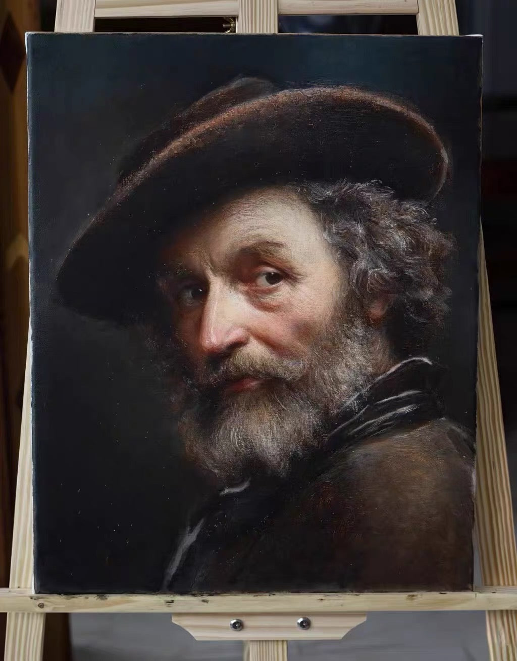 Un retrato de estilo clásico sobre un caballete que muestra a un hombre barbudo con boina y ropa oscuras sobre un fondo oscuro.