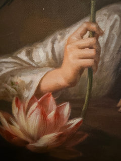 Close-up of a hand holding a lotus stem above a pink lotus blossom